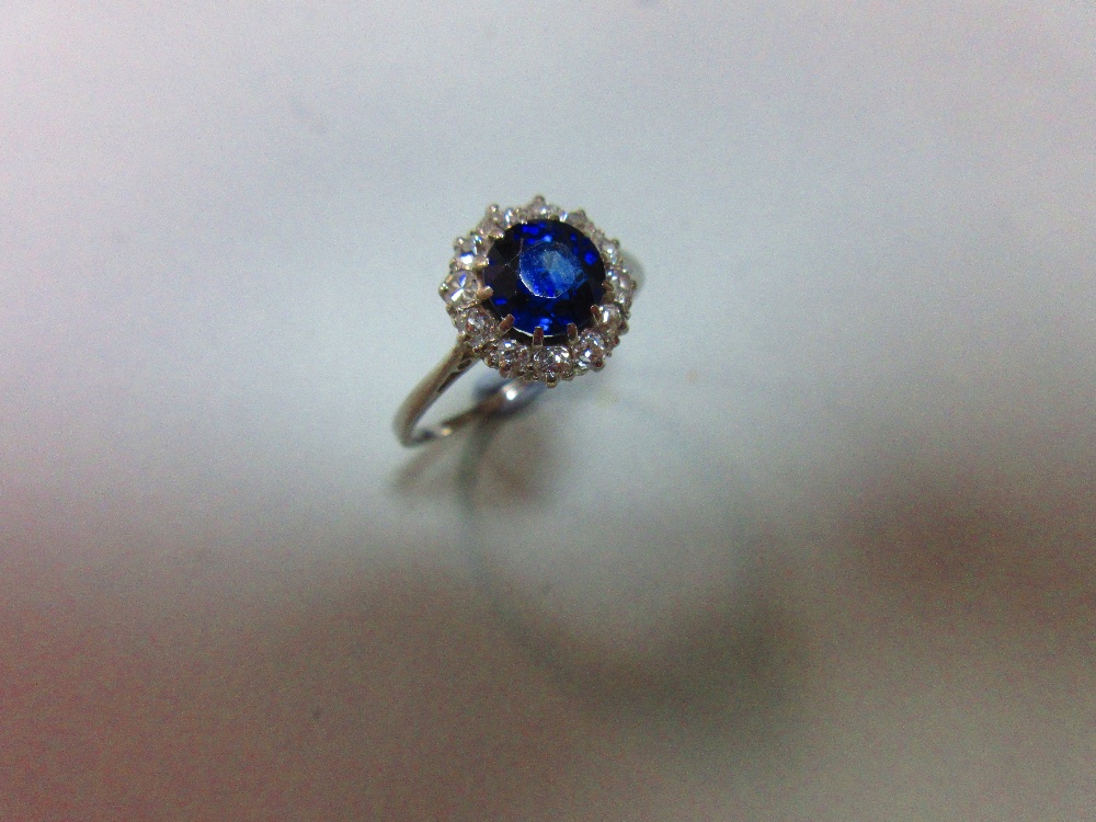 A sapphire and diamond cluster ring, the round cut sapphire in a border of old variously round cut