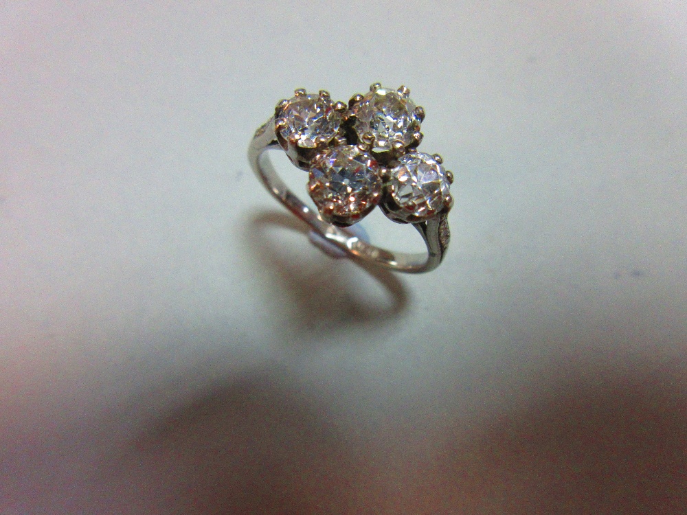 An unusual four stone diamond ring, the old round brilliant cut diamonds claw set in a horizontal