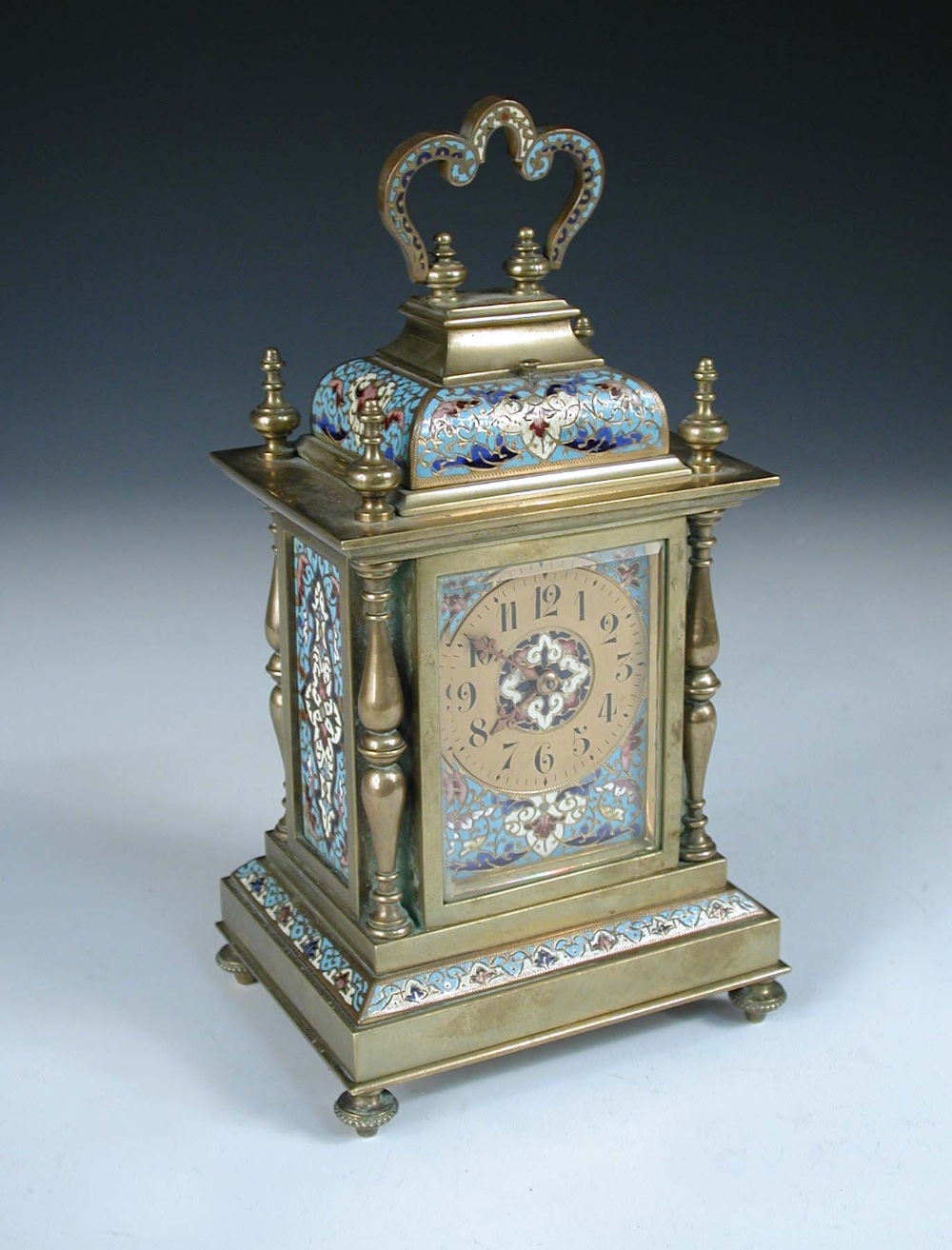 A late 19th century brass and enamelled mantle clock, with folding handle above repeat button,