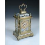 A late 19th century brass and enamelled mantle clock, with folding handle above repeat button,