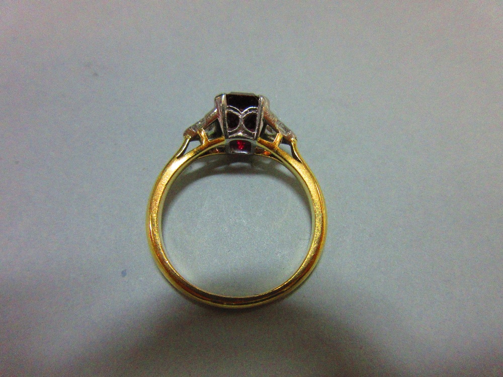 A ruby and diamond three stone ring, the emerald cut ruby four claw set between two trilliant cut - Image 3 of 4
