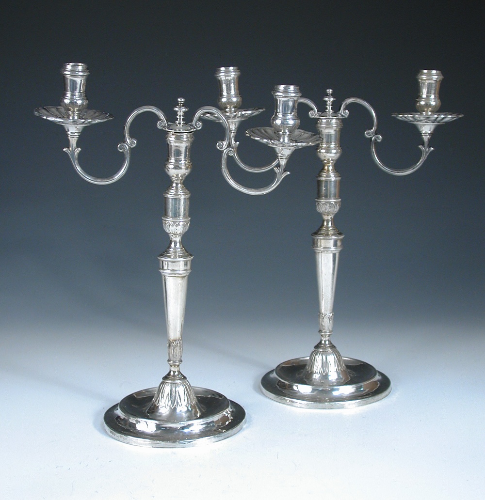 A pair of continental metalwares candelabra, unmarked, each raised from a circular foot with