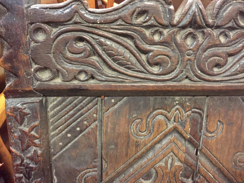 An early 17th century oak wainscote chair, carved in the Medieval style with celtic designs, mask