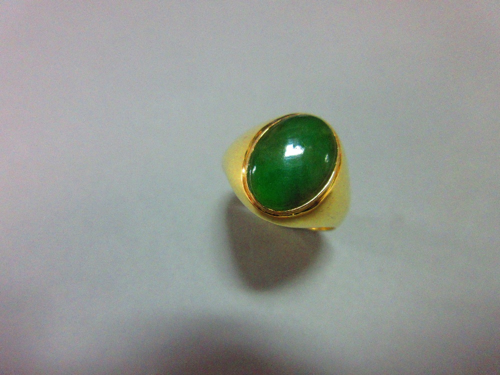 A jade signet form ring, set with a low cabochon polished mid-green jade in rubover setting