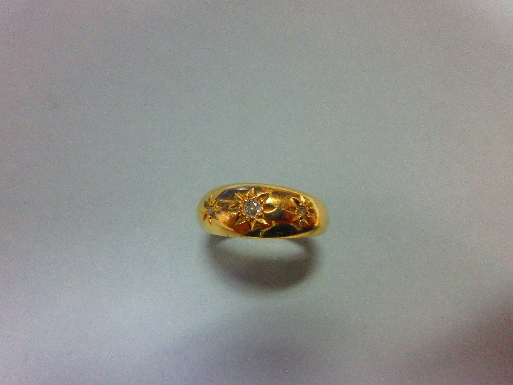 An Edwardian 18ct gold and diamond ring, set with an old round brilliant diamond between two smaller