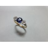A three stone sapphire and diamond ring, claw set with a round cut royal blue sapphire between old