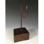 An 18th century iron rushlight holder with later wooden base, the square stem topped by a squared