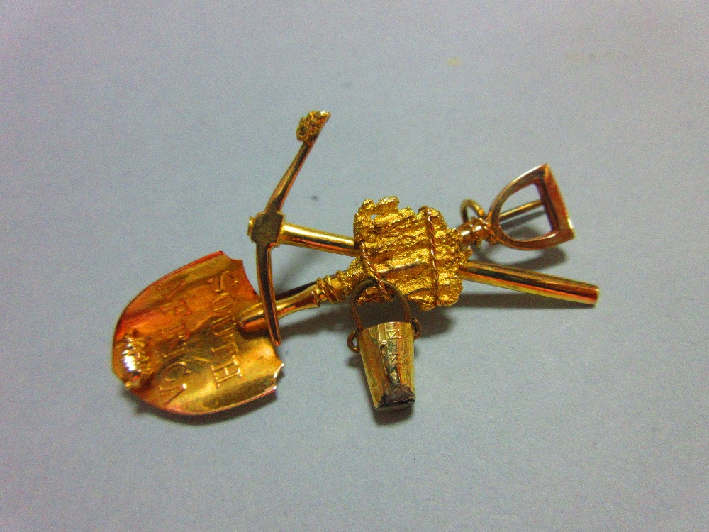 A South Africa gold rush brooch, with shovel, pick and free-swinging bucket tied together, the