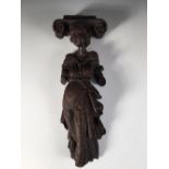 A 17th century oak term, carved as a lady in classical dress supporting an Ionic capital on her head