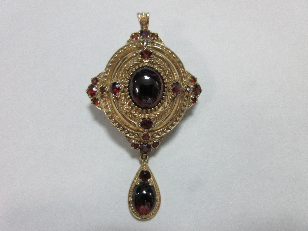 A gold and garnet Holbeinesque pendant / brooch, of oval tiered form, set to the cardinal points