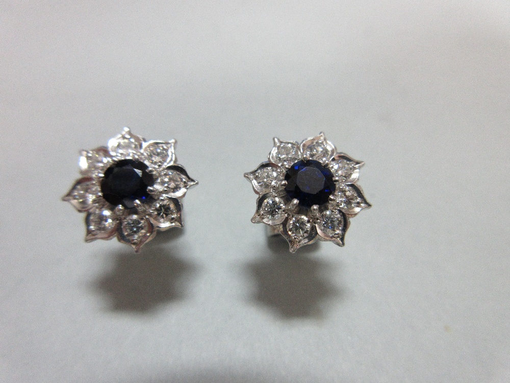 A pair of sapphire and diamond cluster earstuds, each designed as a flowerhead with a round cut