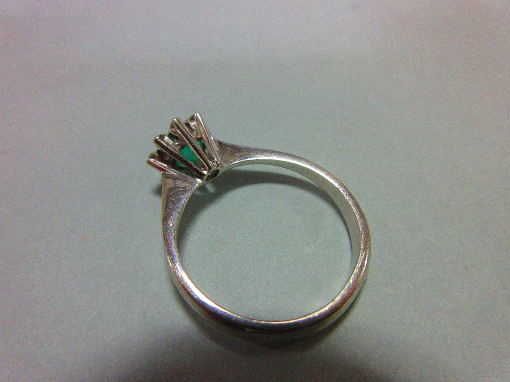 An emerald and diamond ring, set with a round cut emerald in a small petal border of eight single - Image 3 of 4