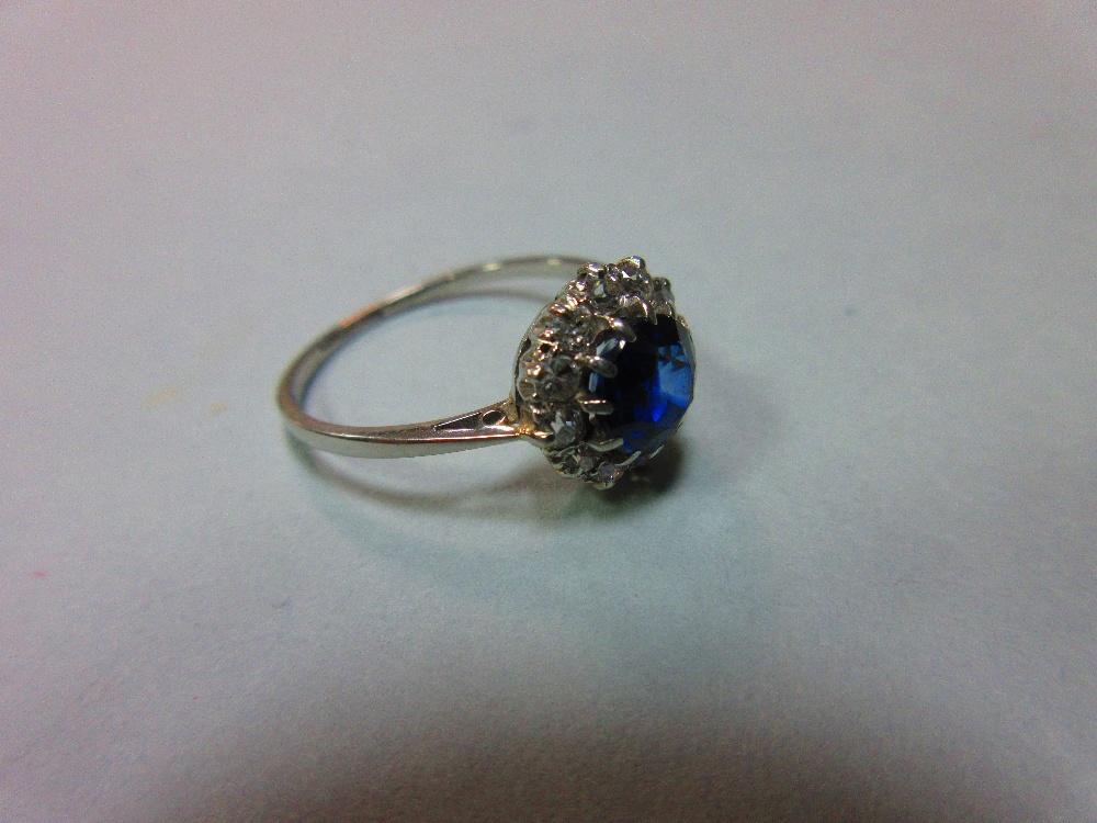 A sapphire and diamond cluster ring, the round cut sapphire in a border of old variously round cut - Image 2 of 5