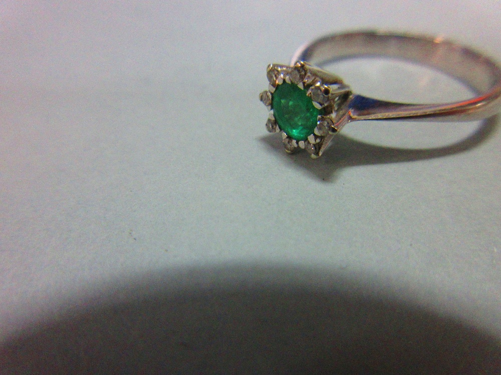 An emerald and diamond ring, set with a round cut emerald in a small petal border of eight single - Image 2 of 4