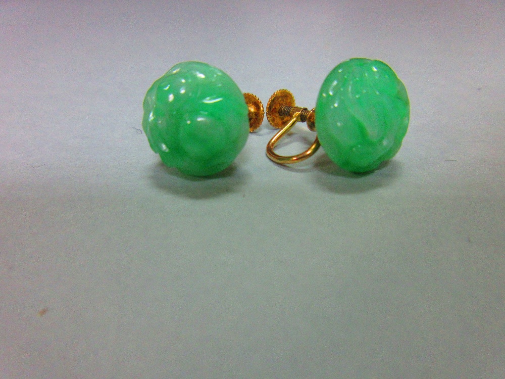 A pair of carved jadeite jade screwback earrings, each bouton of light emerald green mottled jade