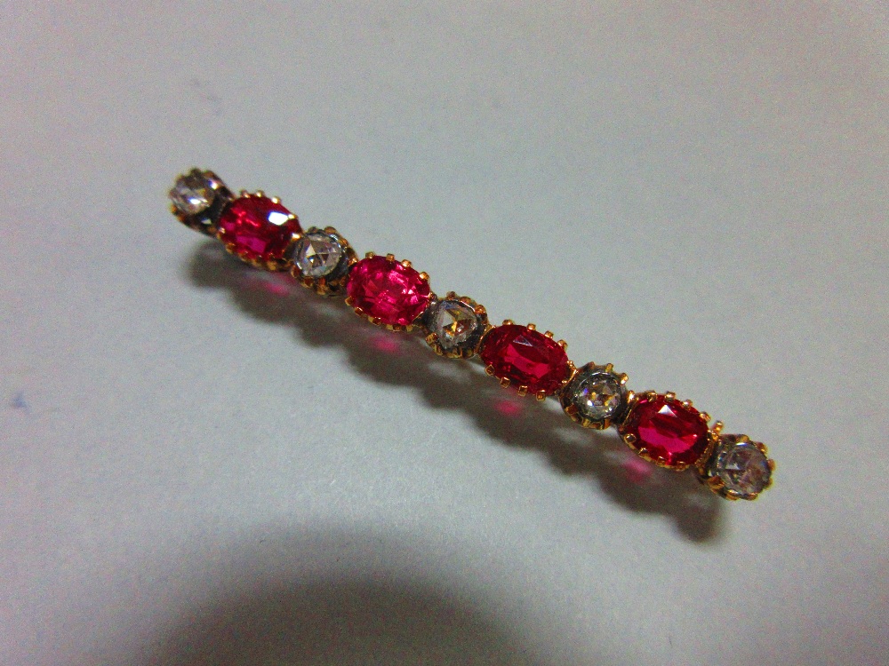 A ruby and diamond brooch, of bar form close set with five rose cut diamonds separated by four