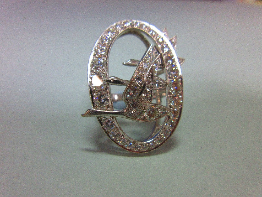 An unusual diamond dress ring, designed as a pierced millegrain edged oval crossed by three flying