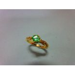 An 18ct gold ring set with a green garnet and diamond highlights, the bright apple green round cut