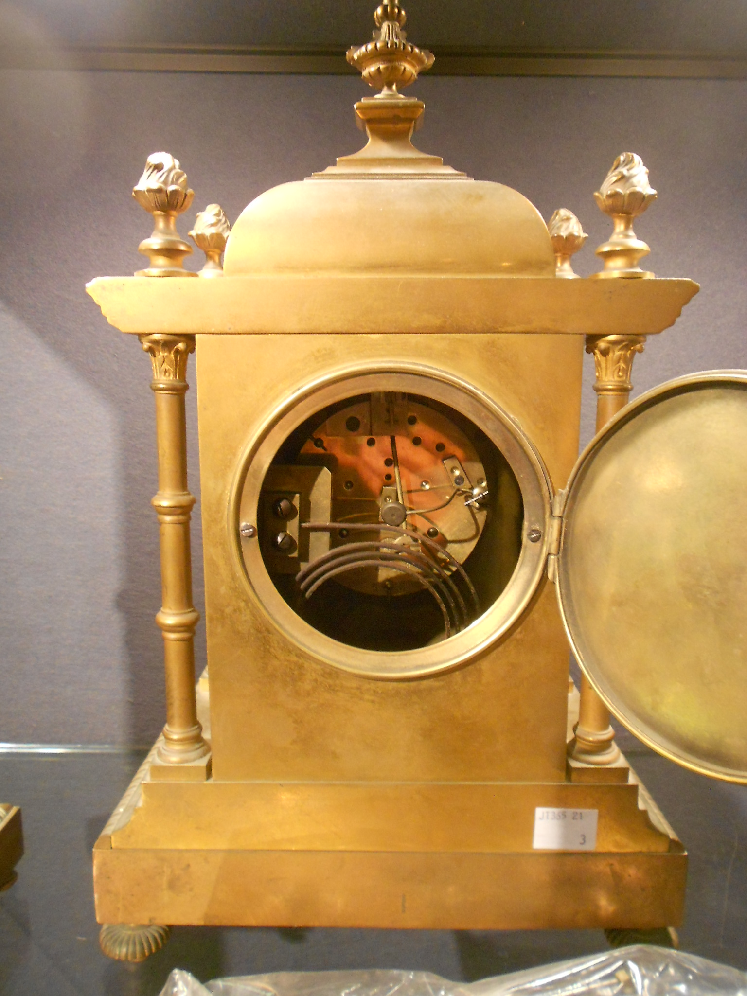 A late Victorian Aesthetic movement clock garniture, the lacquered brass case with domed cresting