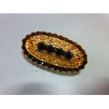 An Italian 18ct gold and garnet brooch, of elongated oval outline delineated by round cut deep red