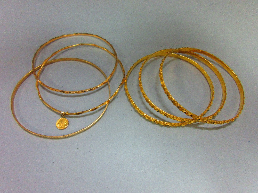 A collection of gold slave bangles, three of hallmarked 22ct gold with faceted diaper patterning,