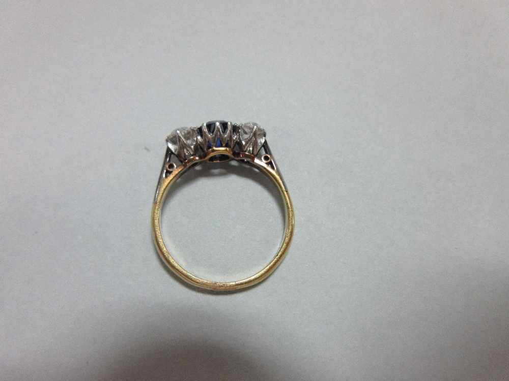 A three stone sapphire and diamond ring, claw set with a round cut royal blue sapphire between old - Image 4 of 7