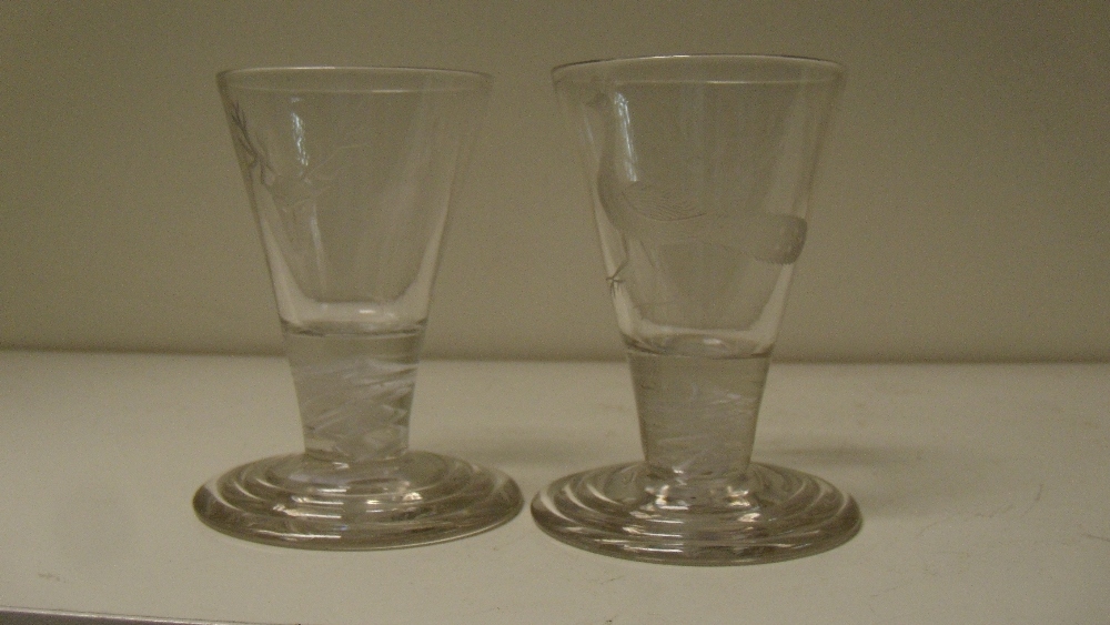 A pair of early 19th century firing glasses, the conical bowls engraved with stags' heads and