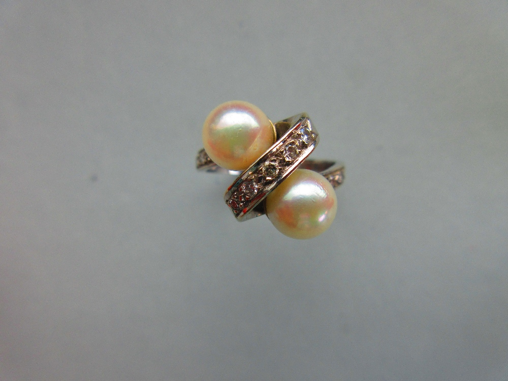 A Continental white gold, pearl and diamond crossover ring, the plain shank set to the front with