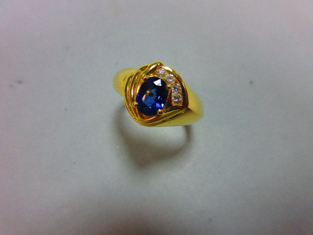 A modern asymmetrical 18ct gold and gemset ring, with a central claw set oval cut vivid blue