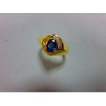 A modern asymmetrical 18ct gold and gemset ring, with a central claw set oval cut vivid blue