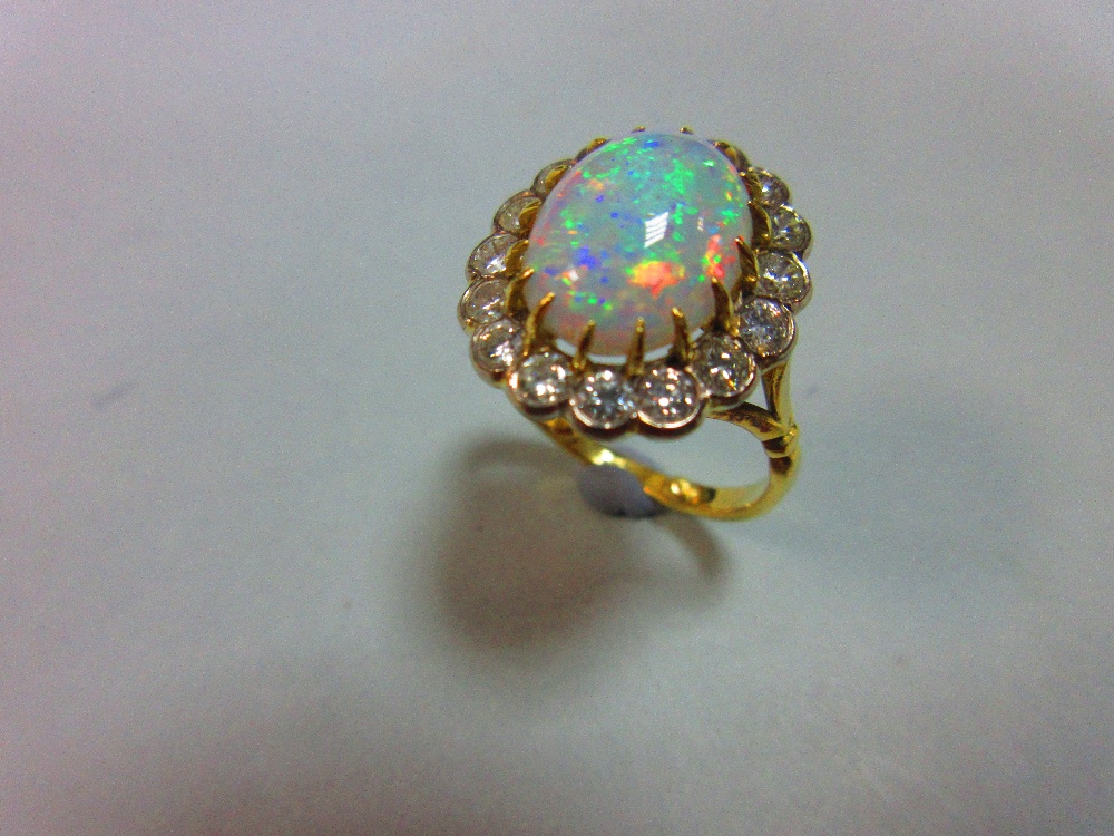 An opal and diamond cluster ring, the oval cabochon opal, displaying a rainbow range of fire, claw - Image 2 of 5