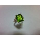 A 1930s style peridot and diamond ring, the emerald cut peridot measuring 10.6 x 8.7mm, four claw