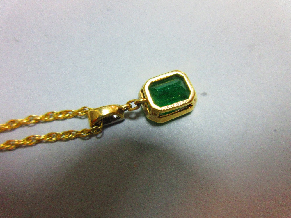 An emerald and diamond pendant set in 18ct gold, with chain, the emerald cut emerald collet set - Image 5 of 5