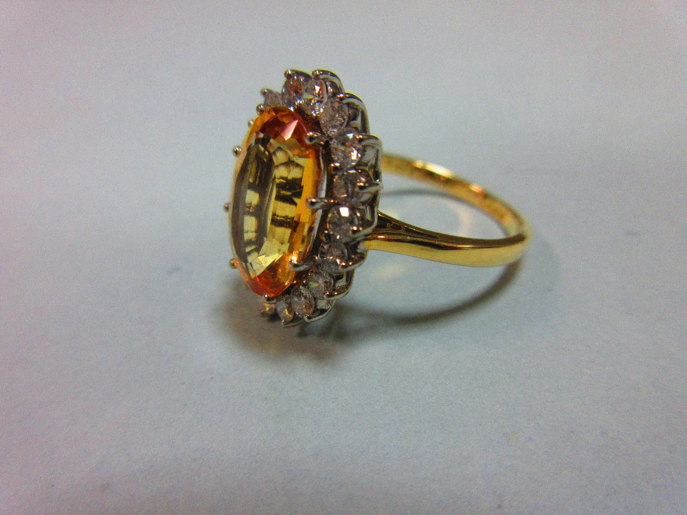 A topaz and diamond cluster ring, the oval mixed cut golden topaz claw set to a border of eighteen - Image 2 of 5