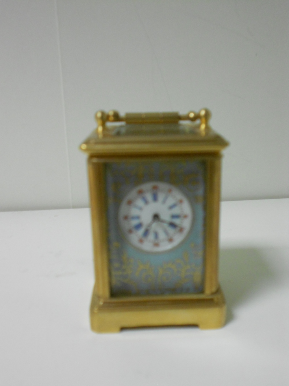 A miniature French porcelain panel gilt brass carriage timepiece, with gilt decorated pale blue