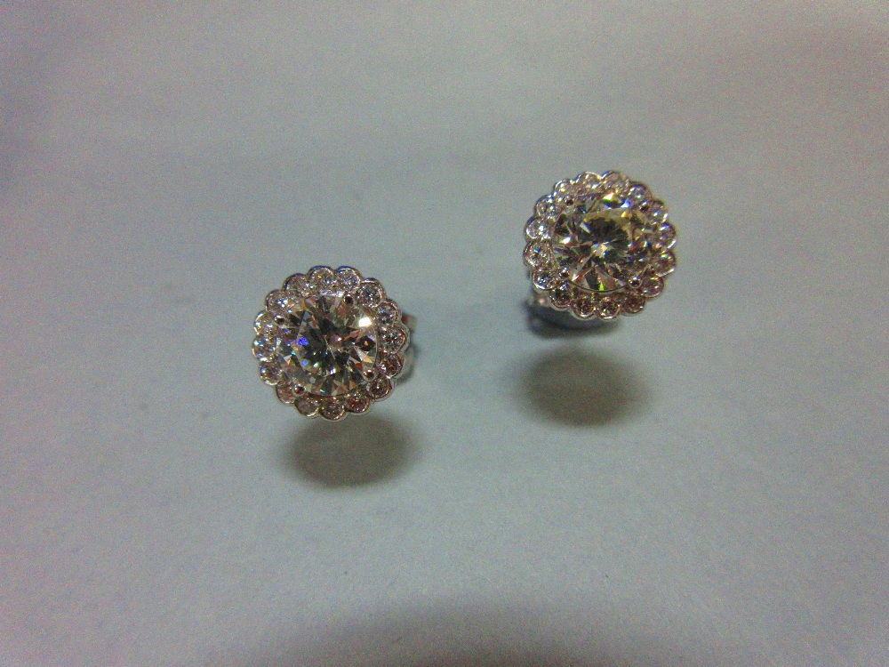 A pair of diamond cluster earstuds, each designed as a four claw set principal round brilliant cut