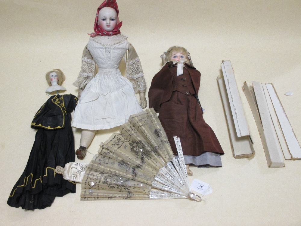 A 19th century bisque head doll with blue eyes (no hair) together with two other dolls and two