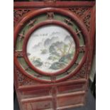 A Chinese wooden panel inset with a porcelain roundel