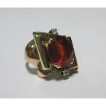 A contemporary dress ring, the oval orange hardstone claw set with a small diamonds in white metal