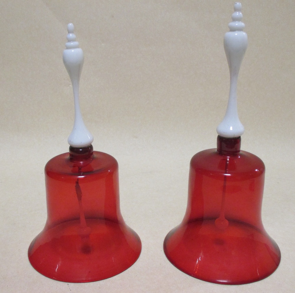 Two late Victorian cranberry glass bells with milk glass handles, 31cm and 28.5cm high
