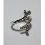 A white gold and diamond crossover ring in the form of a floral sprig, total estimated weight of