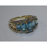 A blue topaz and diamond ring, the five graduated emerald cut topaz, claw set with a narrow