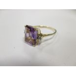 An amethyst and diamond ring, the emerald cut amethyst set in four claws with a small round