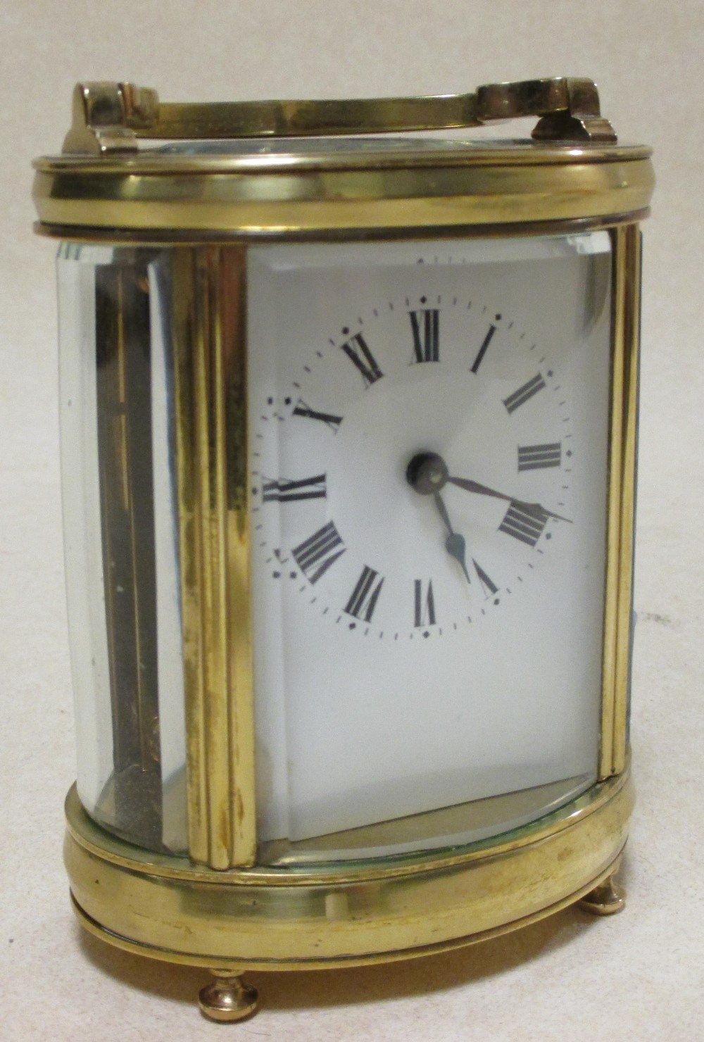 An early 20th century brass carriage clock, the oval body with glass panels, 12cm high handle down