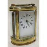 An early 20th century brass carriage clock, the oval body with glass panels, 12cm high handle down