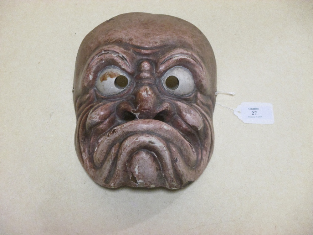 A Kyogen mask, of a grimacing man, his lips raised up towards the whites of his staring eyes, his