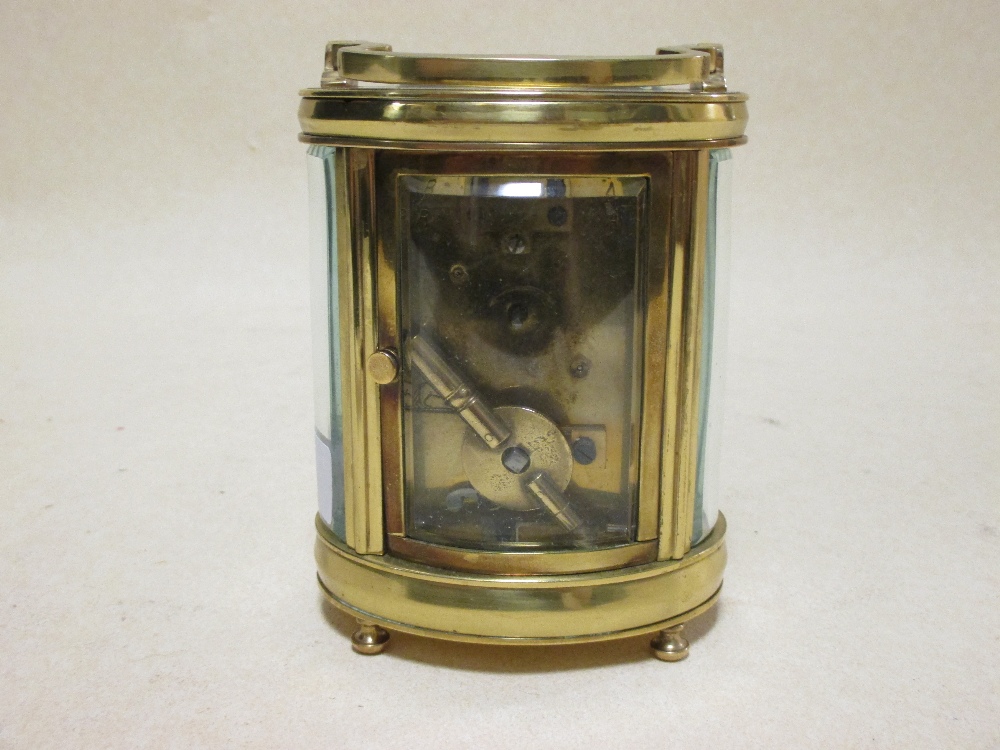 An early 20th century brass carriage clock, the oval body with glass panels, 12cm high handle down - Image 3 of 3