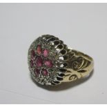 A ruby and diamond cluster ring, the broad flat head of the ring set with eight rubies and