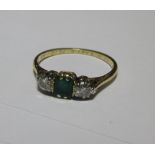 An emerald and diamond ring, the emerald cut emerald flanked by a roudn brilliant diamond to