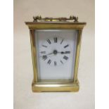 A brass cased carriage clock with white dial and black Roman numerals, 11.5cm high handle down